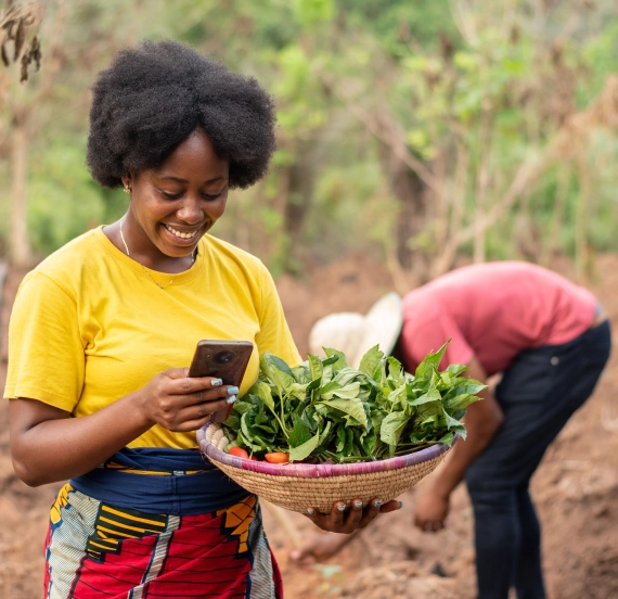 A woman holding a basket of leaves and a man in the background