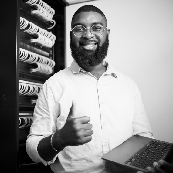 A man holding a laptop and giving a thumbs up